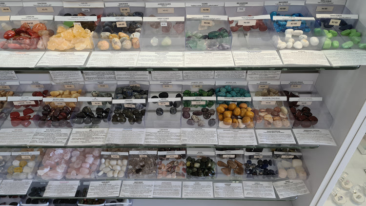 sHOP COUNTER WITH BOXES OF TUMBLED STONES IN A VARIETY OF COLOURS