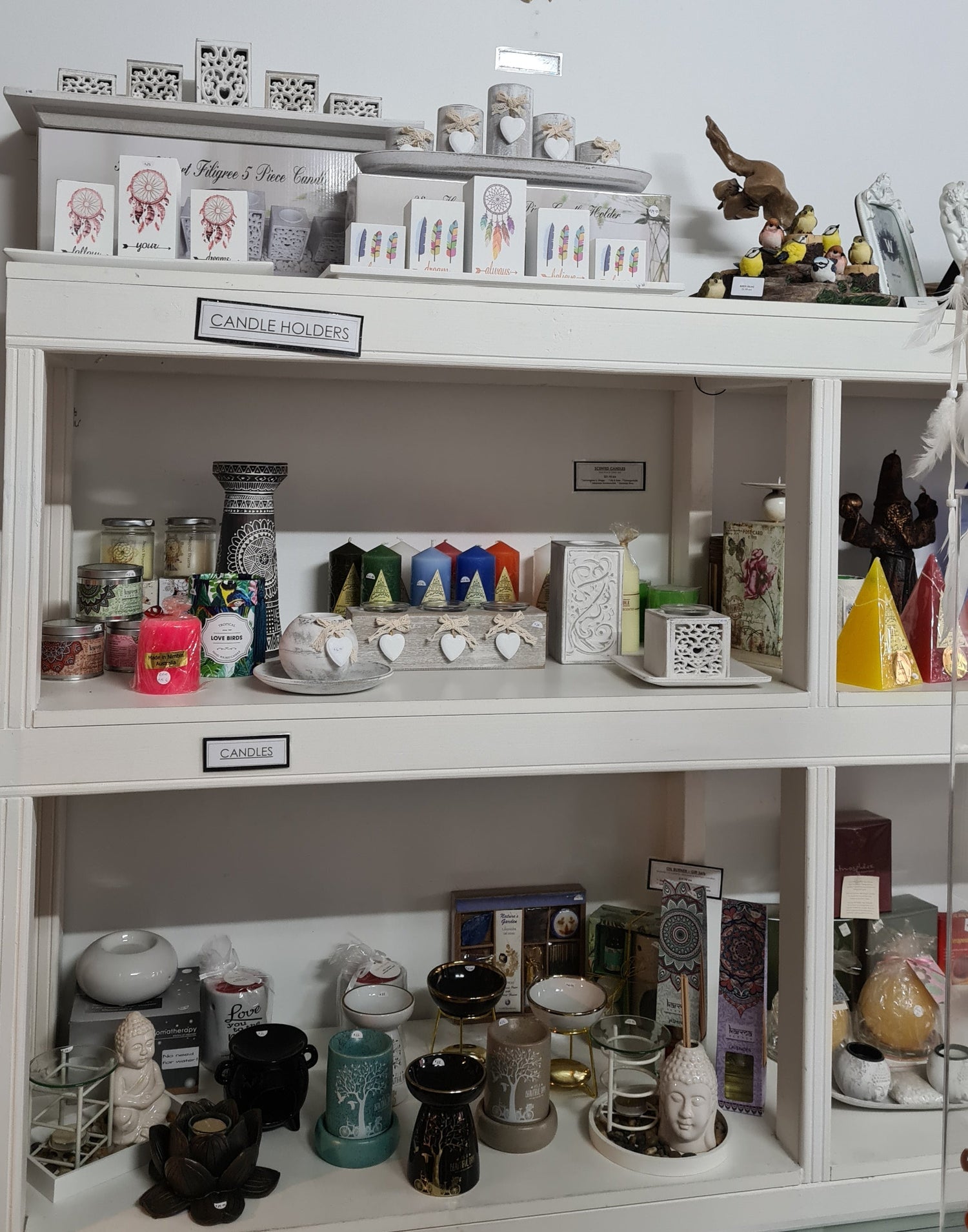 Shelf displaying soy candles and tealight candle holders in boho style