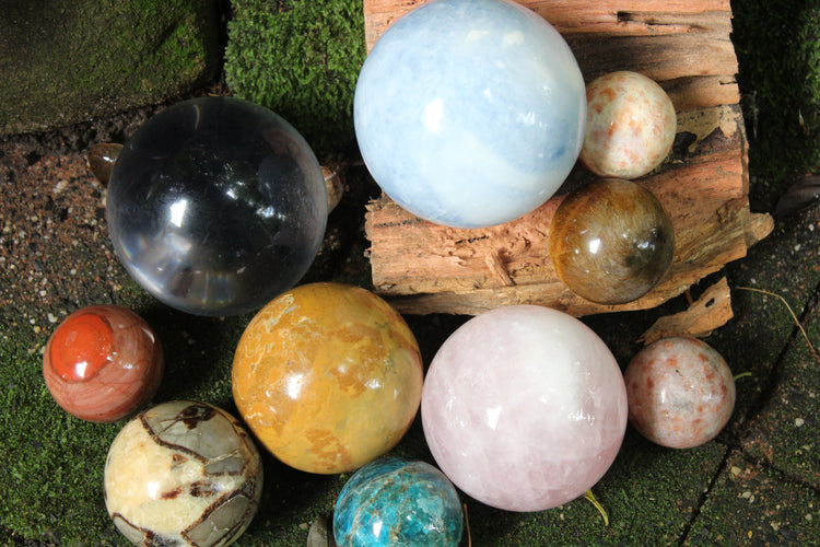 Display of crystal spheres in a variety of crystals and sizes. Staged in garden setting.