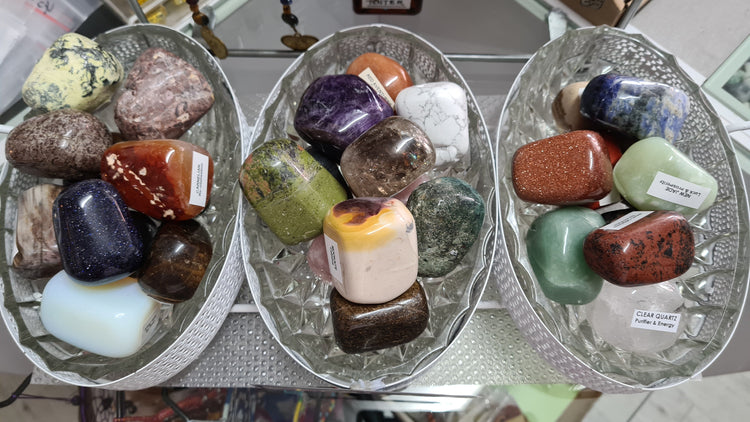 Large tumbled stones displayed in glass bowls. A variety of crystals have been used