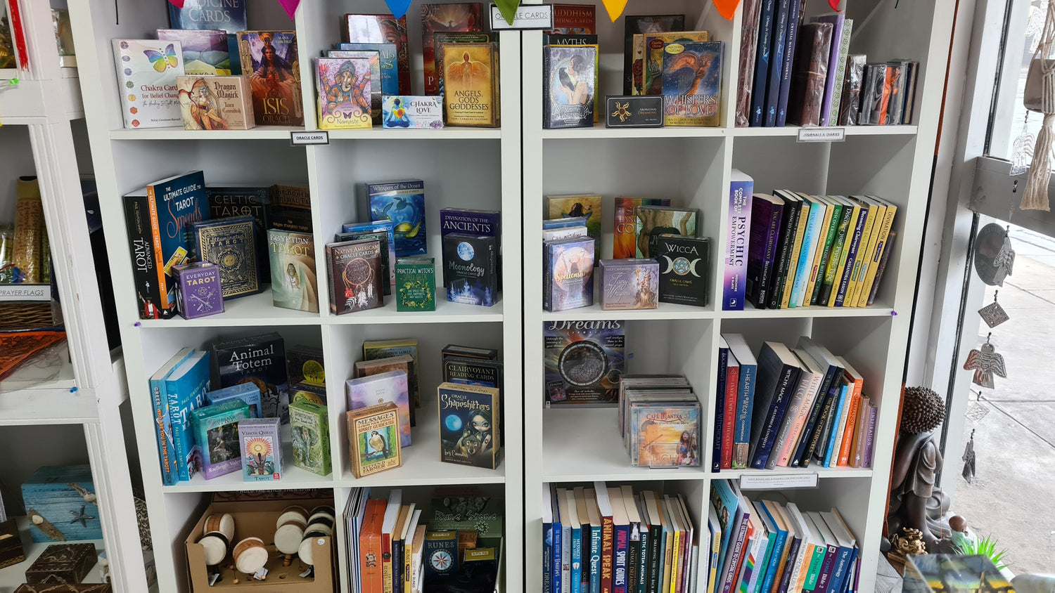 Shelf displaying books, oracle cards, CDs and journals