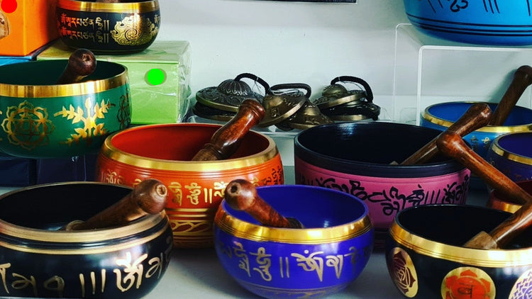 Display of singing bowls in a variety of sizes and colours with striker displayed with bowls